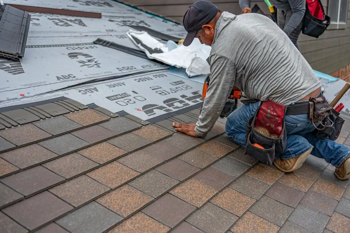 Roofing installer fastening shingles over new underlayment in Warwick, RI